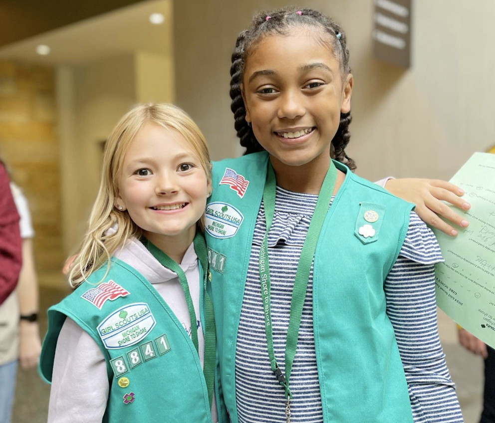 Two girls with their arms around each other's shoulders
