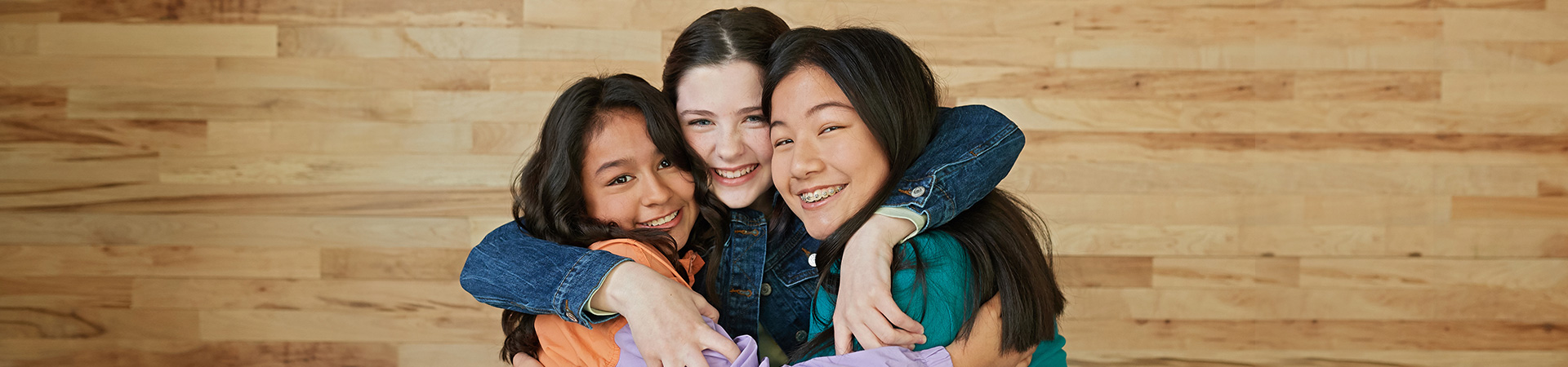  three young girl scouts with their arms wrapped around one another and smiling at the camera 